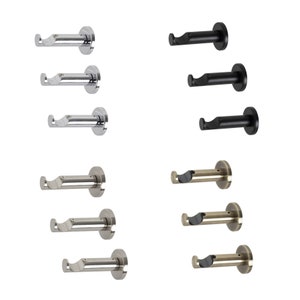 May include: Set of nine curtain rod brackets in three finishes: silver, black, and brass. Each bracket has a round base and a curved arm with a hook at the end.