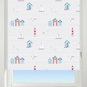 May include: White window blind with a beach-themed pattern. The pattern features red and blue beach huts, sailboats, lighthouses, and seagulls on a white background.