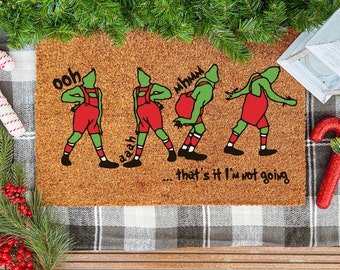 May include: A brown doormat with a green and red illustration of the Grinch from the movie "How the Grinch Stole Christmas". The Grinch is shown in various poses with the text "ooh", "aaah", "mhmm", and "...that's it I'm not going".