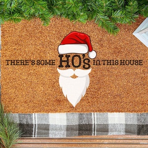 May include: A brown coir doormat with the text "There's some HO'S in this house" and a cartoon image of Santa Claus's face with a red hat and white beard.