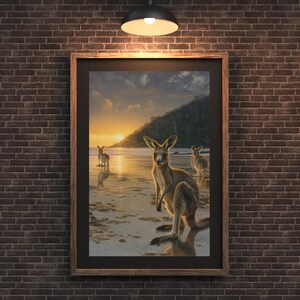 Puede incluir: Impresión enmarcada que presenta tres canguros en una playa al atardecer. La obra muestra a los marsupiales en aguas poco profundas, con un cielo dorado y una silueta de colina. El marco es de madera oscura.