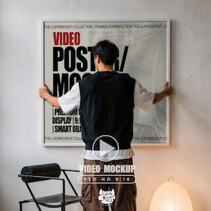 Könnte beinhalten: Eine Person hängt ein weiß gerahmtes Poster mit den Worten "VIDEO POSTER MOCKUP" in Schwarz und Rot auf. Das Poster enthält auch den Text "PREMIUM DISPLAY 9:1 SMART OBJ". Das Bild ist ein Video-Mockup mit dem Text "PSD HD 9:16".
