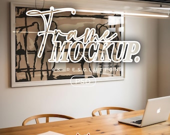 Puede incluir: Un marco de pared rectangular que contiene una impresión abstracta en beige y negro, superpuesto con el texto blanco Frame MOCKUP. 4K RESOLUTION PSD. El marco está montado en una pared lisa sobre una mesa de madera con un portátil y papeles.