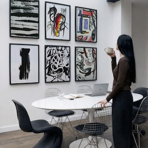 6 A-size frames gallery wall video mockup PSD. A woman hangs black poster mockups in a modern dining room. Premium wall art display for social media.