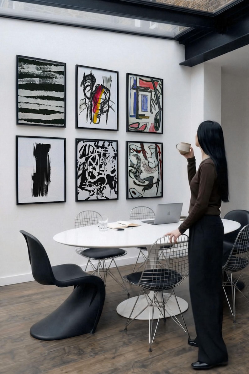 6 A-size frames gallery wall video mockup PSD. A woman hangs black poster mockups in a modern dining room. Premium wall art display for social media.