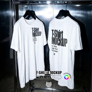 Könnte beinhalten: Zwei weiße T-Shirts hängen an einem Gestell. Jedes Shirt trägt den Text "T-Shirt Mockup" auf der Vorder- und Rückseite. Zusätzlicher Text lautet "4k/300dpi Smart Object Psd Template". Der untere Teil des Bildes trägt den Text "T-SHIRT MOCKUP PSD 4 K RES".