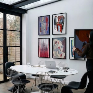 6 A-size frames gallery wall video mockup PSD. A woman hangs black poster mockups in a modern dining room. Premium wall art display for social media.