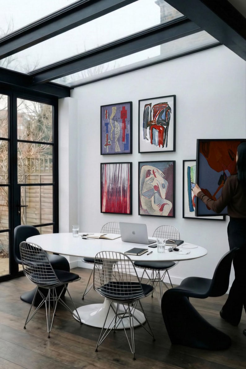 6 A-size frames gallery wall video mockup PSD. A woman hangs black poster mockups in a modern dining room. Premium wall art display for social media.