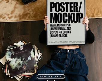May include: A black framed poster mockup featuring the text POSTER/MOCKUP, FRAME MOCKUP PSD, PREMIUM WALL ART DISPLAY 4K, 300 DPI, SMART OBJECTS, and THE LUXYMOCKUP COLLECTION - FRAMED PURRFECTION. A stack of vinyl records sits nearby on a dark wooden floor.