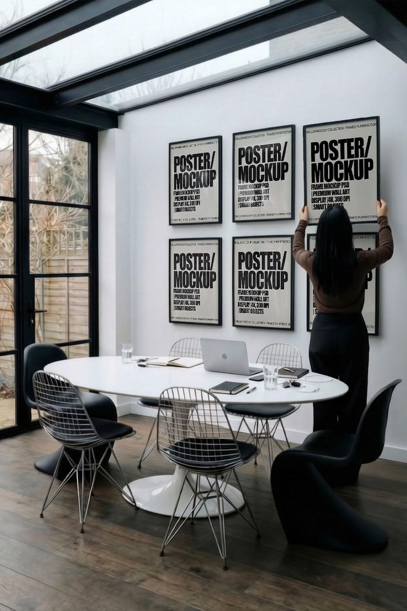6 A-size frames gallery wall video mockup PSD. A woman hangs black poster mockups in a modern dining room. Premium wall art display for social media.