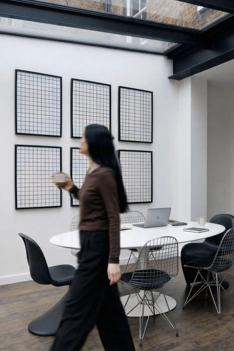 6 A-size frames gallery wall video mockup PSD. A woman hangs black poster mockups in a modern dining room. Premium wall art display for social media.