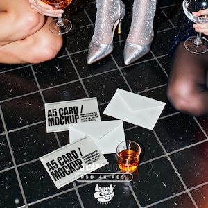 May include: A5 card mockups with white envelopes and a glass of amber liquid on a black tiled surface. The cards have the text "A5 CARD / MOCKUP" in bold, black font. The image also includes a logo and text that reads "PSD 4K RES".