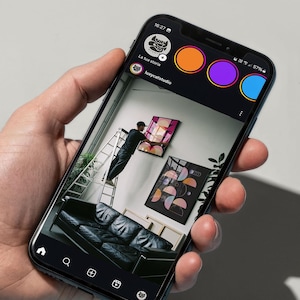 Pode incluir: Um smartphone exibindo uma interface de rede social com o texto Ready to be shared. SOCIAL MEDIA - ETSY - SHOPIFY. A tela mostra um perfil com um sof&aacute; de couro preto, arte de parede geom&eacute;trica emoldurada e uma pessoa em uma escada.