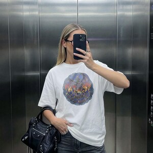 Oversized white t-shirt mockup featuring a trendy woman taking a mirror selfie in an elevator, ideal for streetwear brands. tshirt mock up for e-commerce and social media posts.