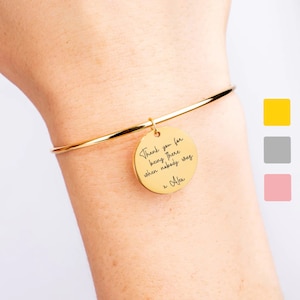May include: Gold bangle bracelet with a round charm that says "Thank you for being there when nobody was x Alex".