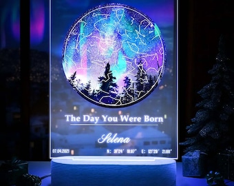 Może przedstawiać: Nocna lampka z przezroczystego akrylu z okrągłym obrazem nocnego, gwieździstego nieba z konstelacjami. Na lampce nadrukowany jest tekst "The Day You Were Born", a także imię, data i współrzędne.