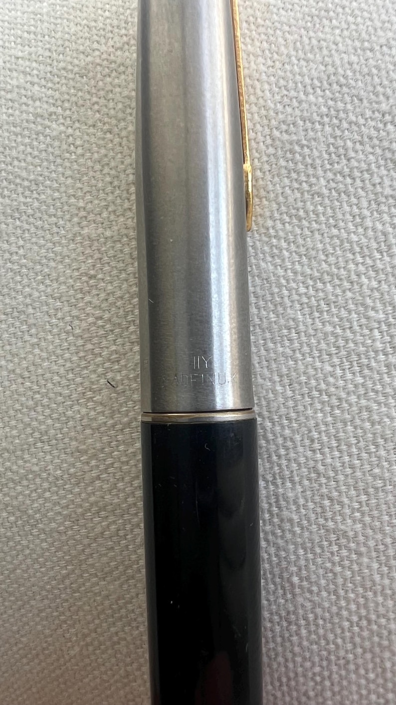 May include: A close-up of a silver and black pen with a gold-colored clip. The pen has the text "MADE IN U.S.A." printed on the barrel. The pen is a writing instrument.