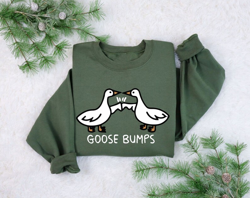 May include: A green sweatshirt with a white graphic of two geese bumping into each other. The text "Goose Bumps" is printed below the geese.