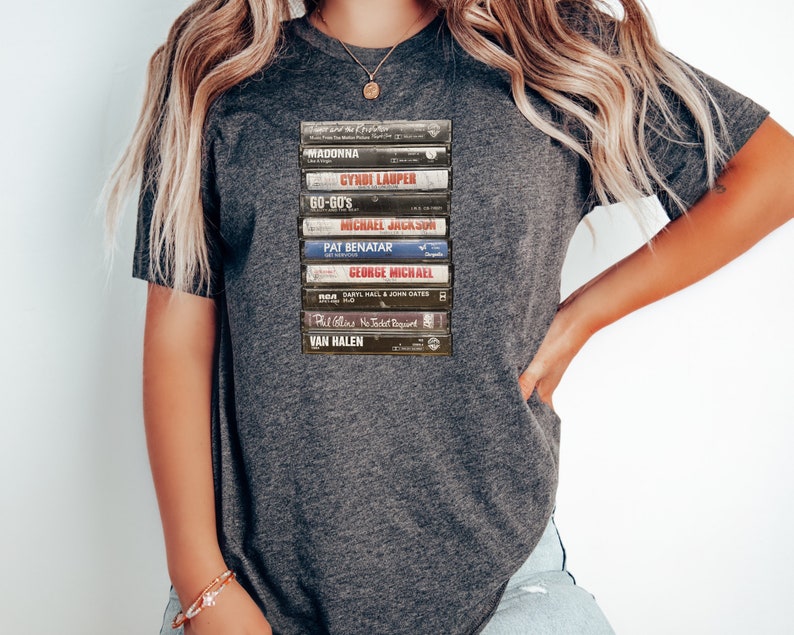 May include: A gray t-shirt with a stack of vintage cassette tapes featuring artists like Madonna, Cyndi Lauper, and Van Halen.