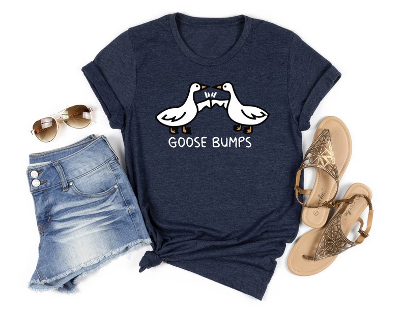 May include: A navy blue t-shirt with a white graphic of two geese bumping heads. The text "GOOSE BUMPS" is printed below the geese.