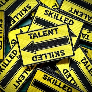 Puede incluir: Un conjunto de parches bordados amarillos y negros. Los parches presentan las palabras "TALENT" y "SKILLED" con una flecha que apunta de talento a habilidad. Los parches son rectangulares y tienen un borde negro.