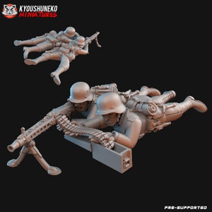 Op de afbeelding: Miniatuurfiguren van soldaten in een liggende schietpositie, die een machinegeweer bedienen. De figuren dragen helmen en militaire uniformen. De afbeelding bevat de tekst "KYOUSJUNEKO MINIATURES" en "PRE-SUPPORTED".