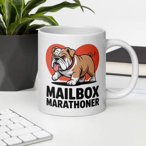 Könnte beinhalten: Weiße Keramiktasse mit einem Cartoon-Bulldoggen-Design, rotem Halsband, vor rotem Herz. Die Tasse trägt die Worte "MAILBOX MARATHONER" in fetten schwarzen Buchstaben.