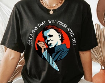 Może przedstawiać: Czarny t-shirt z grafiką Michaela Myersa trzymającego nóż, na czerwonym okręgu. Tekst "GET A MAN THAT WILL CHASE AFTER YOU" jest wydrukowany wokół obrazu. Odzież codzienna.