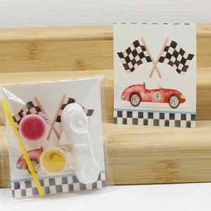 May include: A craft kit with a white race car, two paint pots, a paintbrush, and a card with a red race car and checkered flags. The card says "#4".