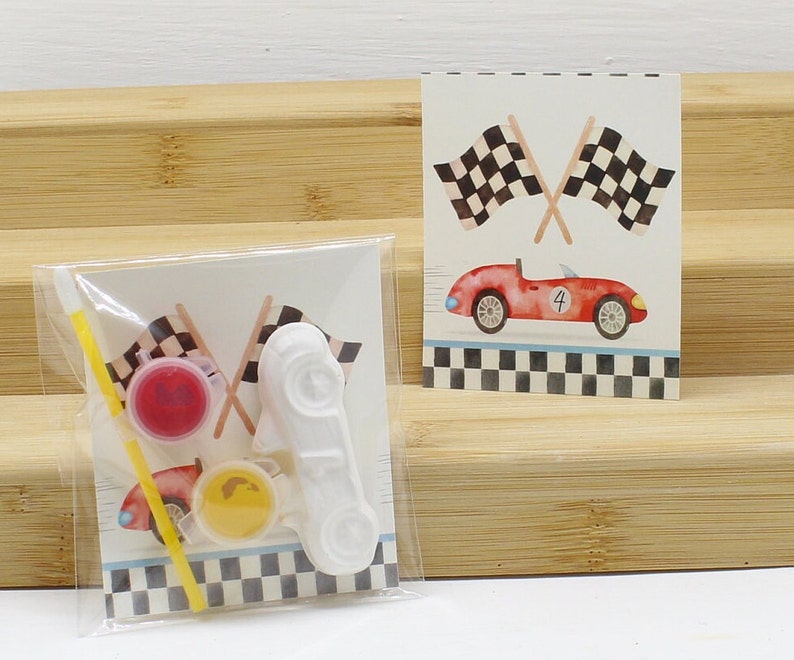 May include: A craft kit with a white race car, two paint pots, a paintbrush, and a card with a red race car and checkered flags. The card says "#4".