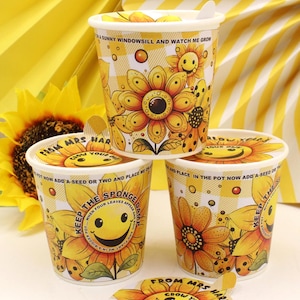May include: Three yellow and white sunflower-themed pots with lids. Each pot features a large sunflower design, a smiling face, and text. The pots are stacked, with a sunflower and yellow background.