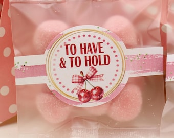 May include: A clear cellophane bag filled with pink candies. The bag is sealed with a decorative sticker that reads "TO HAVE & TO HOLD" with a cherry illustration. The bag is set against a pink polka dot background.