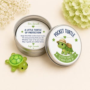 May include: A small green glass turtle figurine next to a round metal tin. The tin lid features a cartoon turtle with a backpack and the text Pocket Turtle A Little Turtle To Keep Close By. Inside the tin is a card with the text For Sarah A Little Turtle Of Protection Keep this little turtle close to you, On every journey that you do. Whether near or far you roam, May it guide you safely home. Safe Travels.