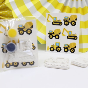 May include: Construction vehicle paint your own craft kit with two paint pots, a bulldozer, a cement mixer, and a dump truck. The kit comes with stickers of construction vehicles.