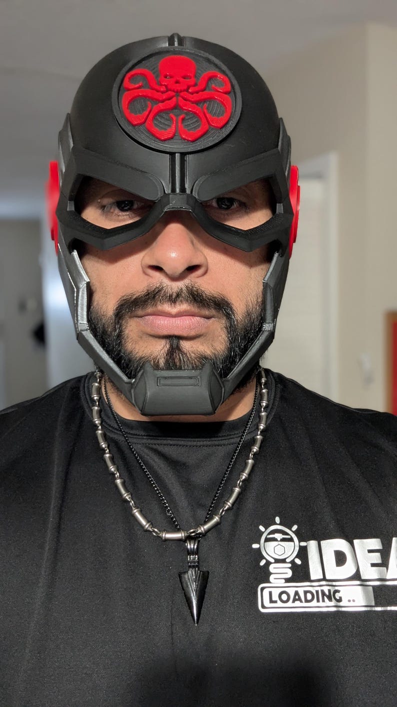 May include: A black and red 3D printed helmet with a skull and tentacles design. The helmet has a visor and a chin guard. The person wearing the helmet is wearing a black shirt with a silver necklace.