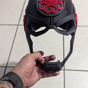 May include: A black plastic helmet with a red skull and tentacles logo. The helmet has a visor and a chin guard.