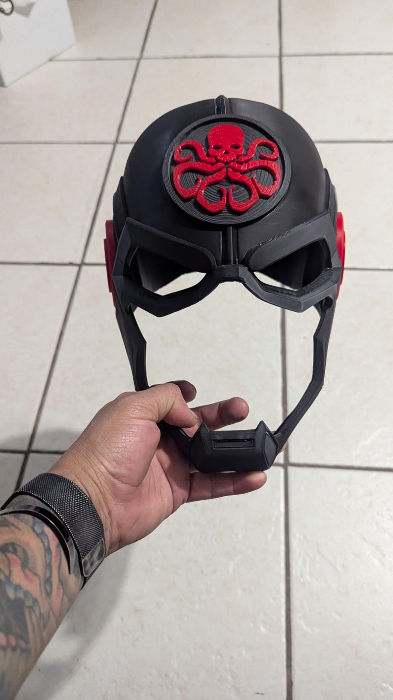 May include: A black plastic helmet with a red skull and tentacles logo. The helmet has a visor and a chin guard.