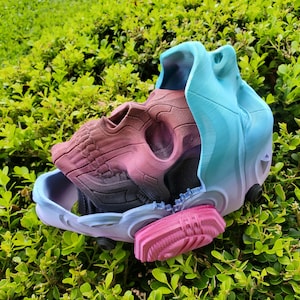May include: A 3D printed skull mask with a blue, pink, and purple color scheme. The mask is split in half, revealing the inside of the skull.