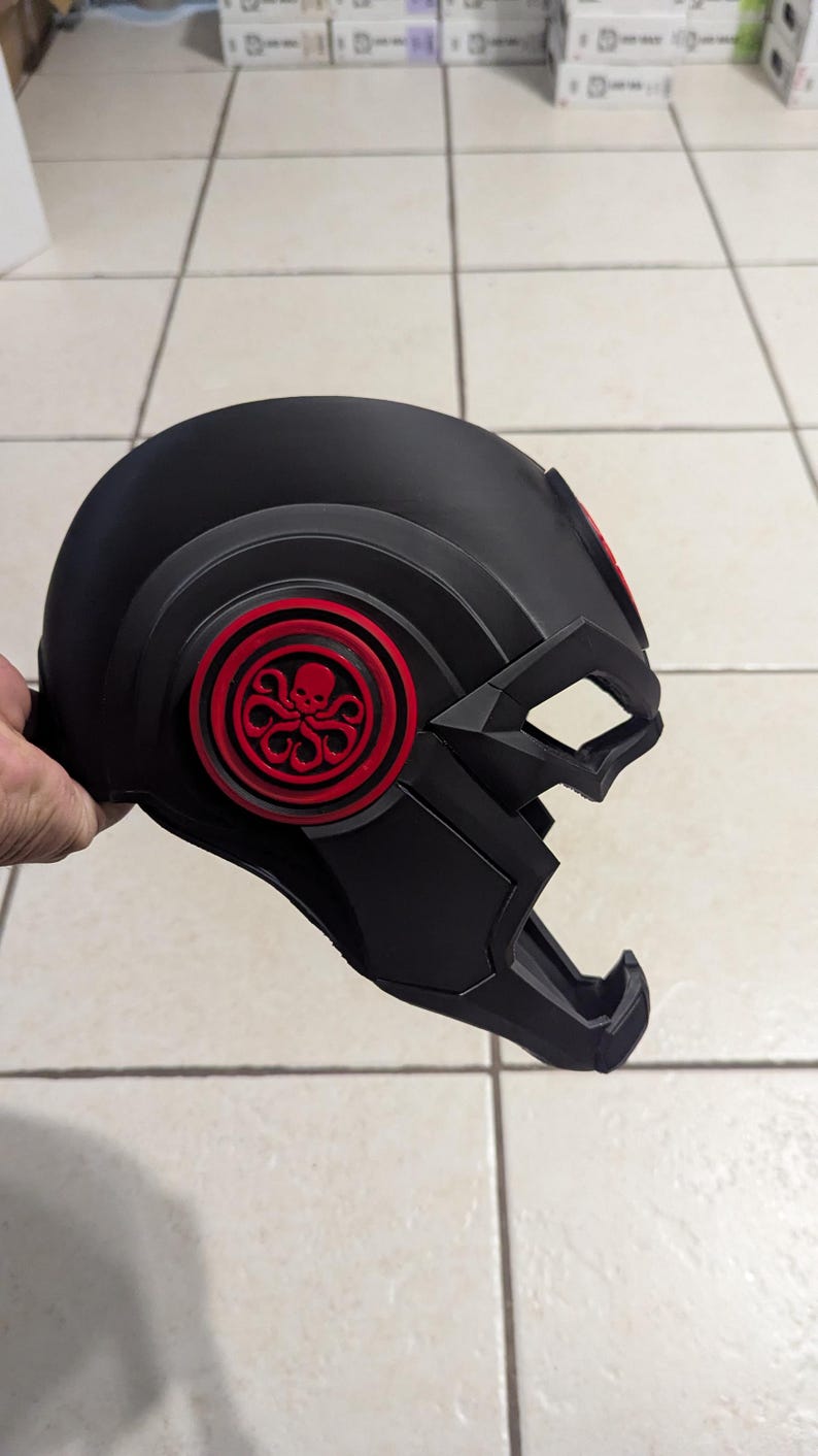 May include: Black helmet with a red Hydra logo on the side. The helmet has a textured surface and a visor.