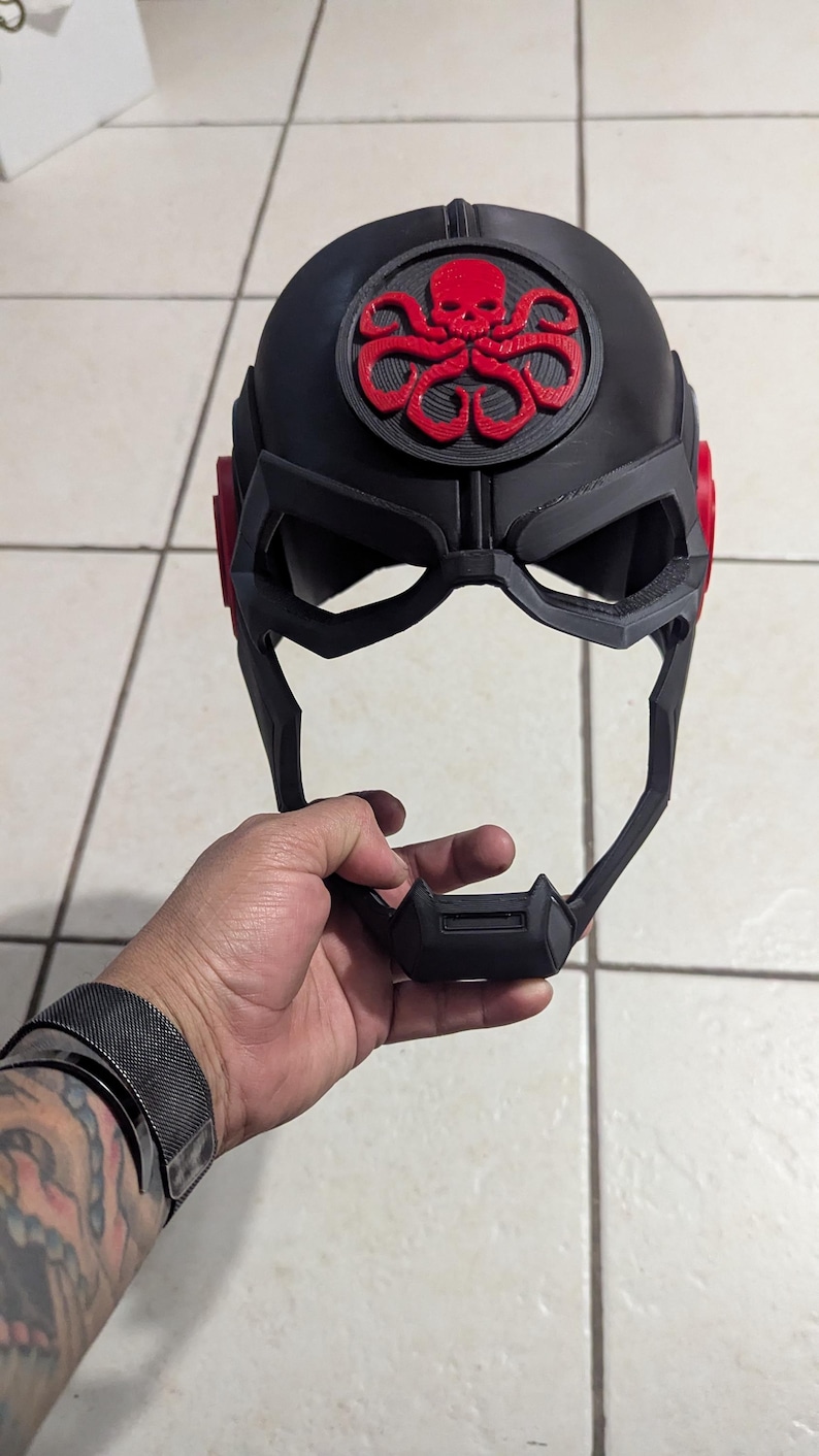May include: A black and red 3D printed helmet with a skull and tentacles design. The helmet has a visor and a chin guard.