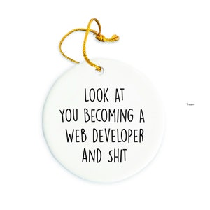 May include: White ceramic ornament with the text "LOOK AT YOU BECOMING A WEB DEVELOPER AND SHIT" in black.