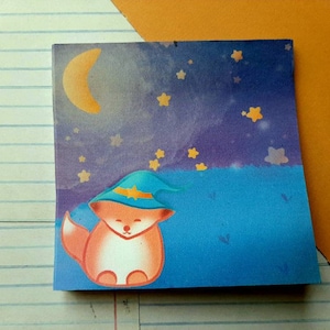 Könnte beinhalten: Ein quadratischer Aufkleber mit einem Cartoon-Fuchs mit blauem Zaubererhut, vor einem Nachthimmel mit Mond und Sternen. Der Fuchs ist orange und weiß, mit einem ruhigen Gesichtsausdruck. Der Hintergrund wechselt von Blau zu Lila.