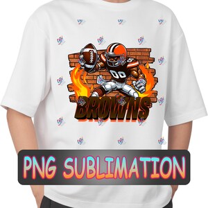以下が含まれることがあります： 白いTシャツに、茶色とオレンジのユニフォームを着た、フットボールを持ったカートゥーンのフットボール選手が、炎のついたレンガの壁に向かって走っている様子が昇華プリントされています。選手の真下に「BROWNS」という文字がプリントされています。