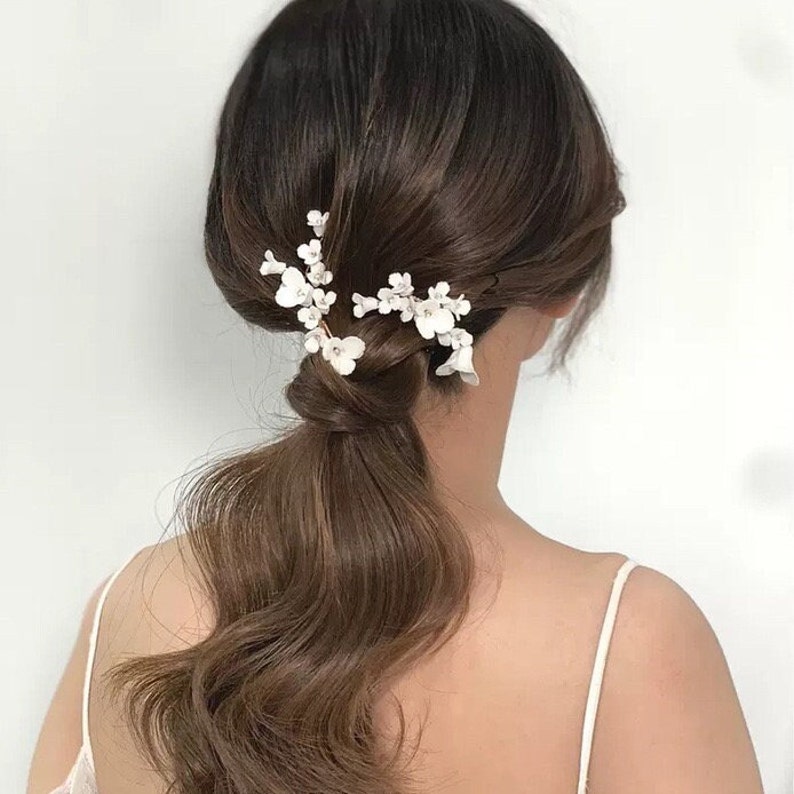 This statement bridal hair clip features carefully handcrafted white porcelain flowers and blossoms, adding an elegant and romantic touch to your hairstyle.