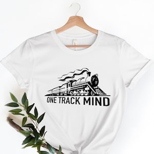 May include: White t-shirt with a black and white illustration of a train engine and the text "ONE TRACK MIND".