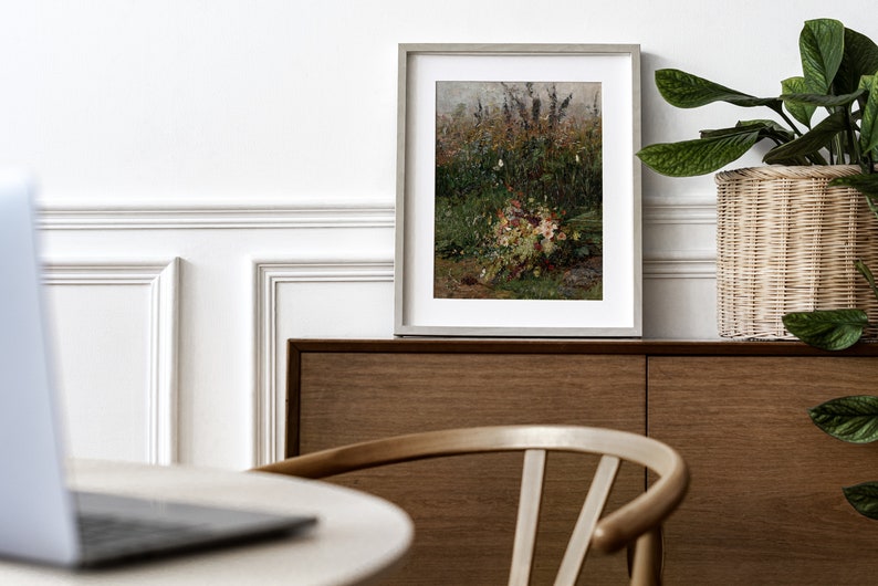Pode incluir: Uma pintura emoldurada de um buqu&ecirc; de flores silvestres em um campo. A pintura est&aacute; em uma moldura cinza clara e est&aacute; pendurada em uma parede acima de um arm&aacute;rio de madeira.