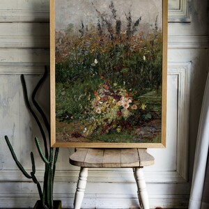 Pode incluir: Uma pintura emoldurada de um buqu&ecirc; de flores silvestres em um campo. As flores s&atilde;o em tons de rosa, branco e amarelo, e h&aacute; borboletas voando ao redor delas.