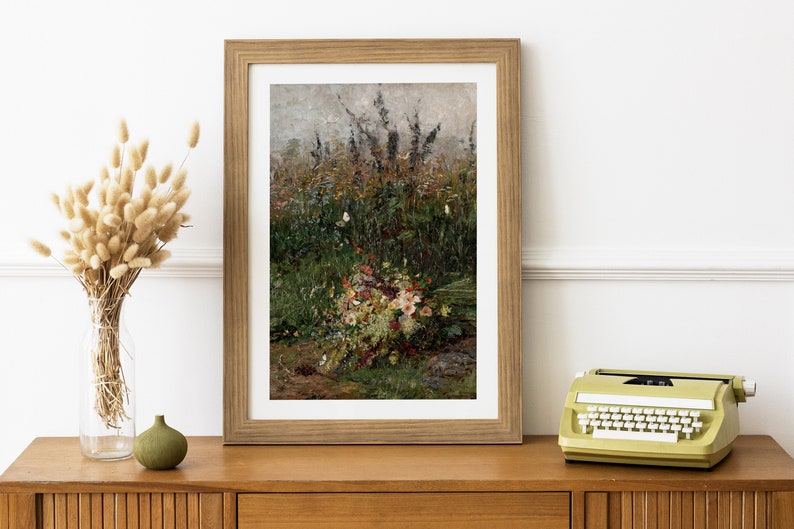 Pode incluir: Uma pintura emoldurada de um buqu&ecirc; de flores silvestres em um campo. As flores s&atilde;o principalmente brancas e rosadas, com alguns toques amarelos e roxos. O fundo &eacute; um verde e marrom desfocado.