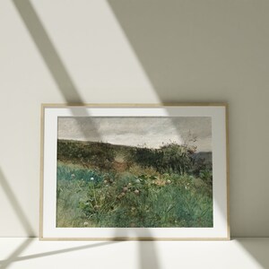May include: A framed landscape art print featuring a field of green grass and wildflowers under a cloudy sky. The artwork has a vintage aesthetic with muted colors and a natural wood frame.