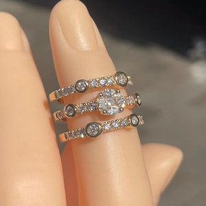 May include: Three gold rings with a central oval-shaped diamond and smaller diamonds set in the bands.
